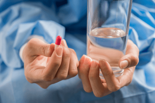 woman-s-hand-pours-medicine-pills-out-bottle Woman taking medicine